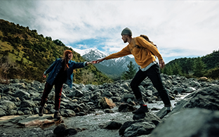 Potential Opdualag patient helping a friend hike a rocky terrain.