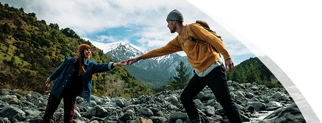 Potential Opdualag patient helping a friend hike a rocky terrain.